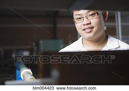 Stock Image - Asian man working in technology repair shop. Fotosearch