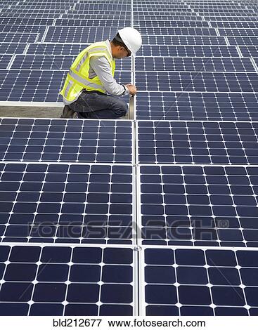Stock Photo - Asian technician working on solar panels. Fotosearch