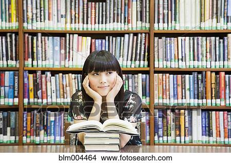 Asian woman daydreaming in library View Large Photo Image Picture - Asian woman daydreaming in library. Fotosearch