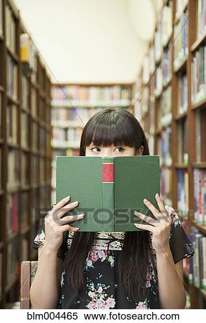 Stock Photography - Asian woman reading book in library. Fotosearch