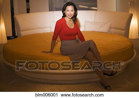 Stock Image - Asian woman sitting on round bed. Fotosearch