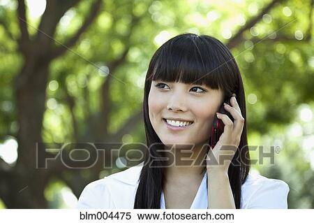 Asian woman talking on cell phone View Large Photo Image Stock Photography - Asian woman talking on cell phone. Fotosearch