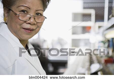 Picture - Asian woman working in technology repair shop. Fotosearch