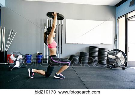 Stock Image - Asian woman working out in gym. Fotosearch