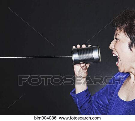 Stock Photograph - Asian woman yelling into tin can phone. Fotosearch
