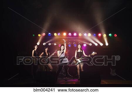 Stock Image - Asian women singing and playing electric guitar onstage. Fotosearch