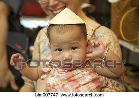 Stock Photo - Baby girl wearing Asian hat. Fotosearch