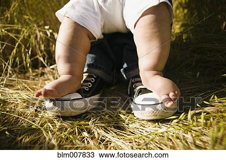 Stock Image - Baby's feet on top of father's feet. Fotosearch