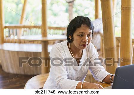 Balinese woman using laptop at table View Large Photo Image Stock Photo - Balinese woman using laptop at table. Fotosearch