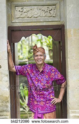 Stock Photograph - Balinese worker smiling in wood archway. Fotosearch