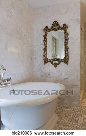 Stock Photograph - Bathtub and mirror in ornate bathroom. Fotosearch