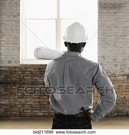 Stock Photo - Black architect wearing hard-hat and holding blueprints. Fotosearch