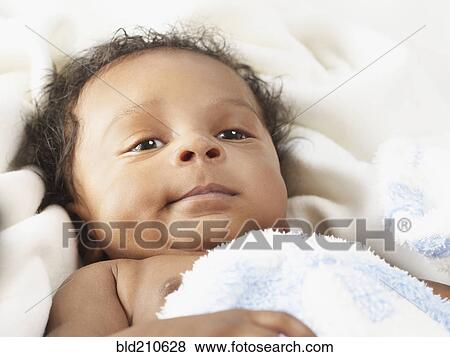 Stock Photo - Black baby laying on bed. Fotosearch