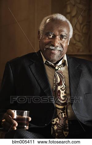 Stock Image - Black businessman drinking cocktail. Fotosearch