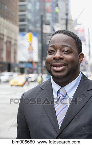 Stock Image - Black businessman smiling on urban street. Fotosearch