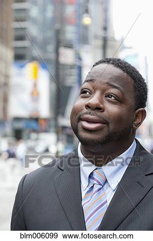 Stock Photo - Black businessman smiling on urban street. Fotosearch