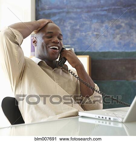 Stock Image - Black businessman talking on telephone. Fotosearch