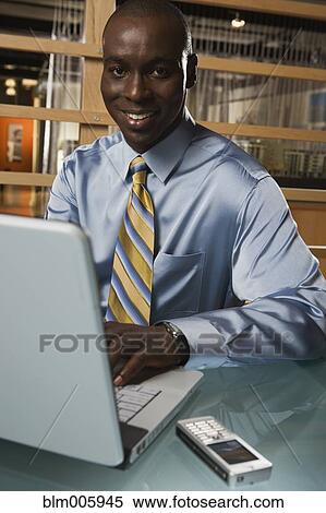 Stock Photography - Black businessman typing on laptop. Fotosearch