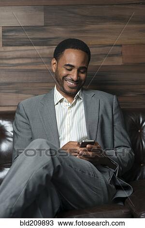 Black businessman using cell phone in office View Large Photo Image Stock Image - Black businessman using cell phone in office. Fotosearch