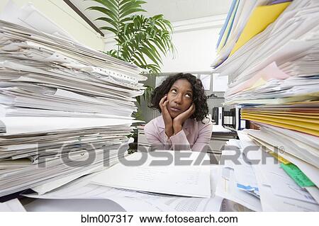 Black businesswoman between stacks of paperwork View Large Photo Image Stock Photo - Black businesswoman between stacks of paperwork. Fotosearch