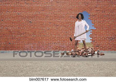 Stock Photo - Black businesswoman breaking through brick wall. Fotosearch