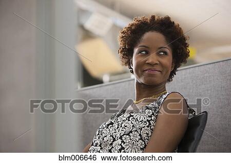 Stock Photograph - Black businesswoman sitting in office cubicle. Fotosearch