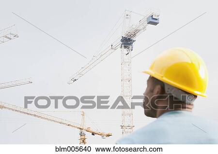 Black construction work in hard-hat looking at crane View Large Photo Image Stock Image - Black construction work in hard-hat looking at crane. Fotosearch