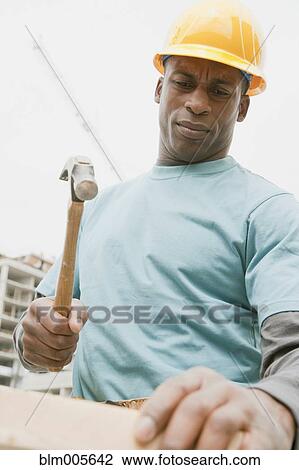 Black construction worker hammering wood View Large Photo Image Stock Image - Black construction worker hammering wood. Fotosearch