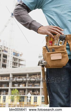 Stock Image - Black construction worker wearing tool belt. Fotosearch