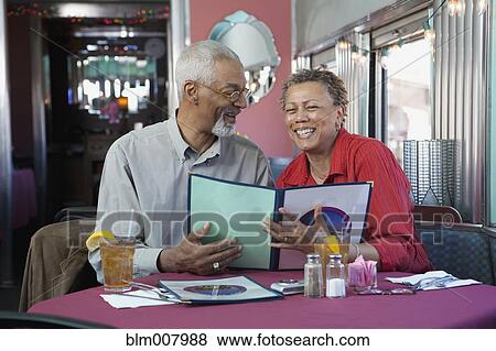 Stock Photo - Black couple reading menu in restaurant. Fotosearch