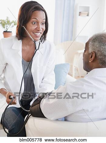 Stock Photo - Black doctor checking senior man's blood pressure. Fotosearch