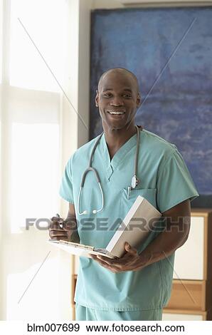 Black doctor in scrubs holding medical chart View Large Photo Image Stock Photo - Black doctor in scrubs holding medical chart. Fotosearch