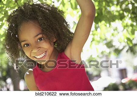 Stock Image - Black girl smiling outdoors. Fotosearch
