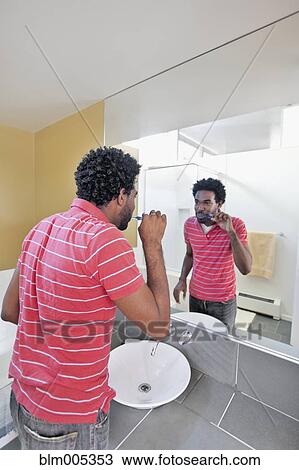 Black man in bathroom brushing teeth View Large Photo Image Stock Image - Black man in bathroom brushing teeth. Fotosearch