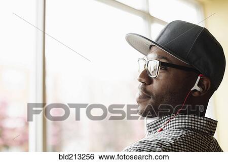 Stock Photograph - Black man listening to headphones indoors. Fotosearch