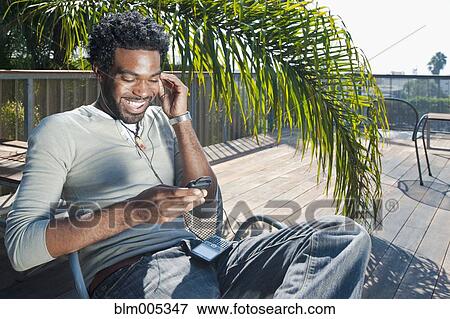 Black man listening to mp3 player on patio View Large Photo Image Stock Photo - Black man listening to mp3 player on patio. Fotosearch