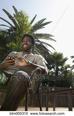 Stock Image - Black man listening to mp3 player outdoors. Fotosearch