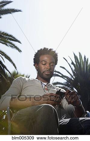 Stock Photo - Black man listening to mp3 player outdoors. Fotosearch