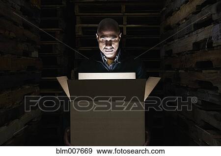Stock Photo - Black man looking into glowing box. Fotosearch