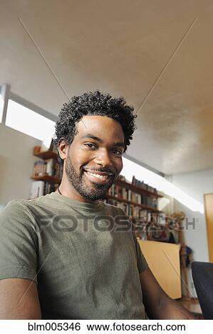 Stock Photograph - Black man smiling in living room. Fotosearch