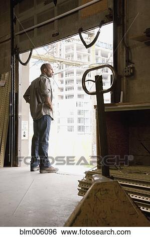 Stock Photograph - Black man standing on warehouse loading dock. Fotosearch
