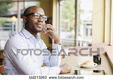 Black man talking on cell phone in coffee shop View Large Photo Image Stock Image - Black man talking on cell phone in coffee shop. Fotosearch