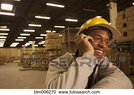Stock Image - Black man talking on cell phone in warehouse. Fotosearch