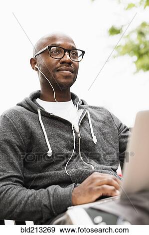 Black man using laptop and earphones outdoors View Large Photo Image Stock Photo - Black man using laptop and earphones outdoors. Fotosearch