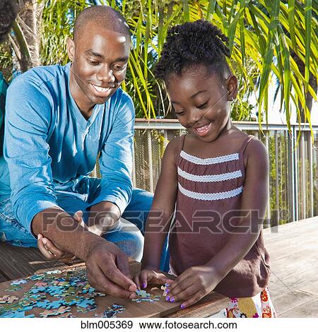 Black man with daughter solving puzzle View Large Photo Image Stock Photo - Black man with daughter solving puzzle. Fotosearch