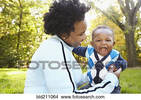 Picture - Black mother and toddler son playing in park. Fotosearch