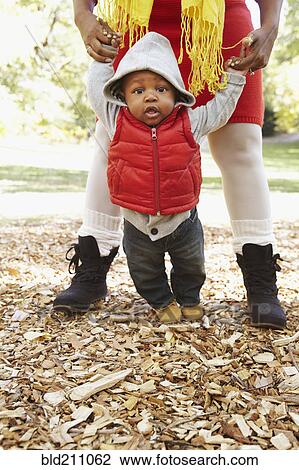 Stock Image - Black mother and toddler son playing in park. Fotosearch