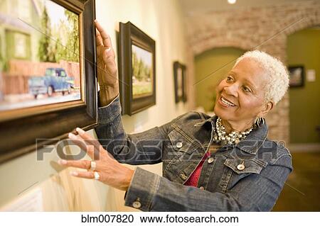 Stock Image - Black woman admiring painting in gallery. Fotosearch