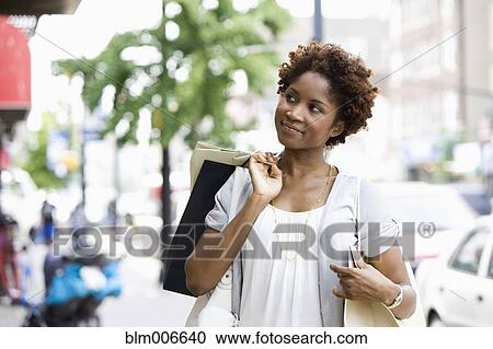 Black woman carrying shopping bags in city View Large Photo Image Stock Image - Black woman carrying shopping bags in city. Fotosearch