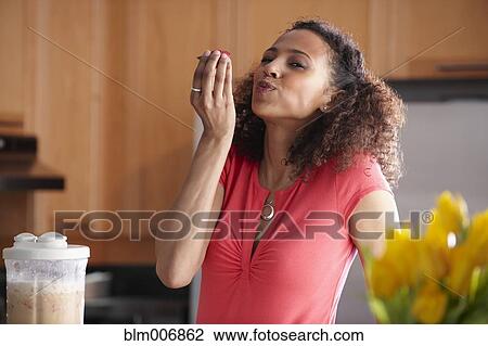 Black woman eating fruit in kitchen View Large Photo Image Stock Image - Black woman eating fruit in kitchen. Fotosearch
